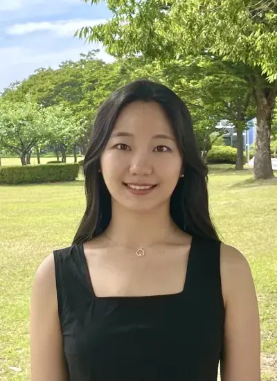 Photo of Jini Kim on a green lawn with trees in the distance