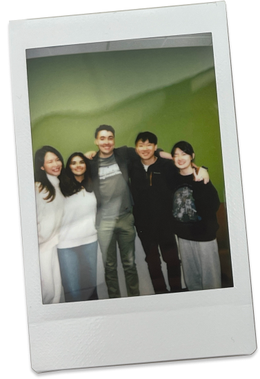 Polaroid photo of team huddled together against MHCI green wall