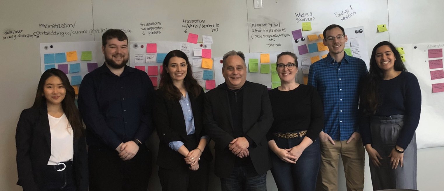 Gov AI + MHCI team members stand side by side in front of a white board with many insights