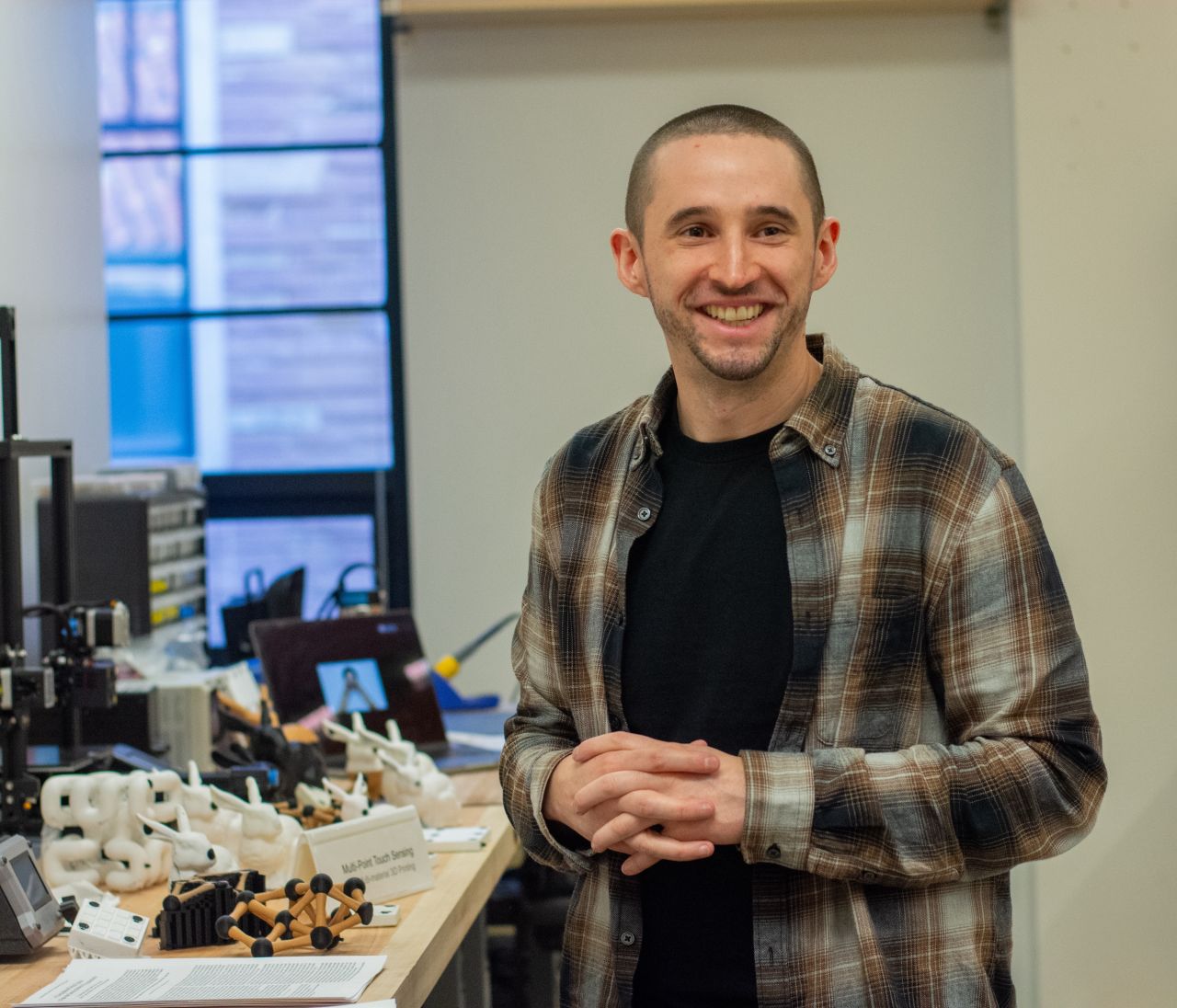 Mike Rivera stands beside a work bench with many projects and papers