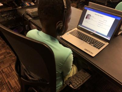 A middle school student is seated at a laptop during introductions to their tutor, a university student.