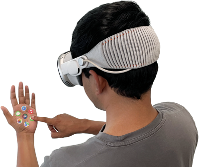 A man with dark hair wears a virtual reality headset and touches his palm, which is superimposed with icons for popular smartphone apps.