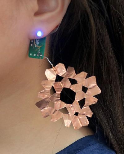 A close-up shot of an earring in human's ear, attached to a circuit board.