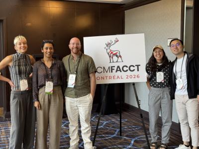 a small group of 5 community members stand near ACM FAccT signage 