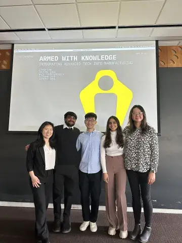 Team MHCI x ARM Institute stands side by side at the front of a classroom on presentation day