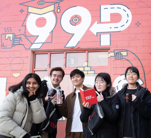 5 team members of the MHCI 99P labs team stands in front of a red wall painted with 99P