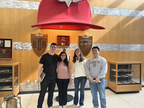 Four team members of Team AirDrop stand under a large red hat