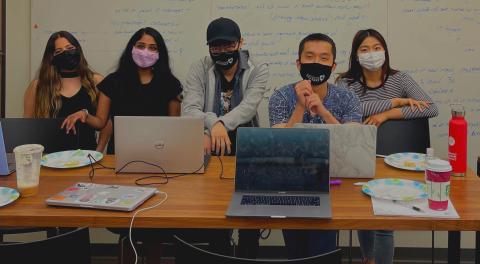 Team photo of 5 students behind a table in the MHCI Lab