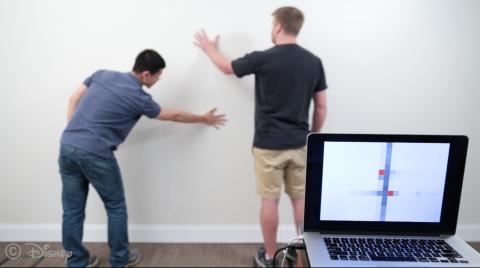 a person touches a wall in 2 places which is recognized by the wall's sensors and displayed on a nearby laptop screen