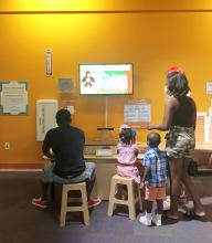 2 adults and 2 children play with the Norilla system in a museum