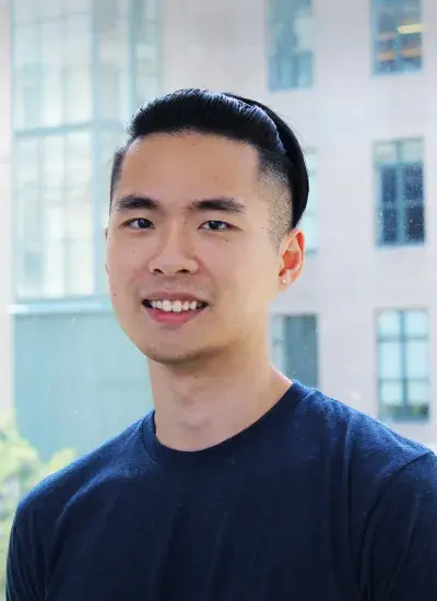 Howie Wang in front of window with campus building in background