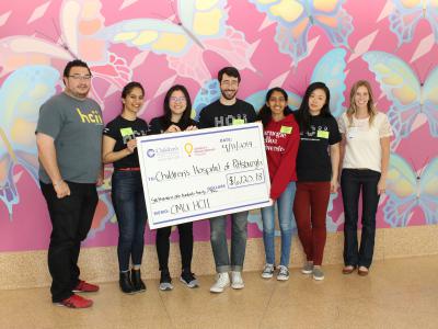 six people from CMU MHCI stand with rep from UPMC Foundation for check presentation at UPMC Children's Hospital