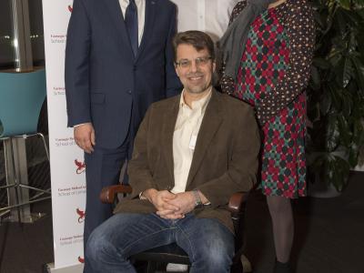 Ken Koedinger is seated in Hillman Professorship chair, while interim CMU president, dean of SCS, and director of HCII stand behind him