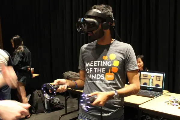 an undergraduate student wears a VR headset during the annual Meeting of the Minds, an undergraduate research event