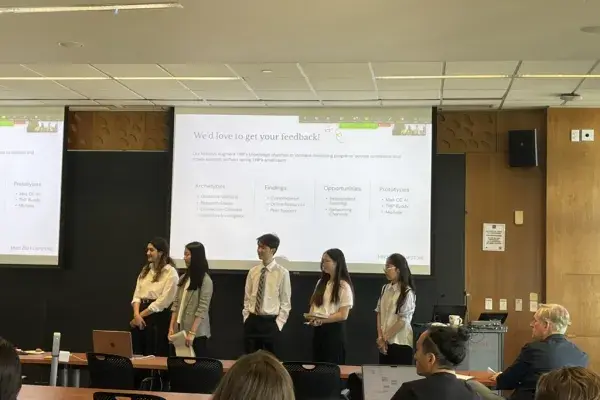 5 students on the Mentoring Partnership team stand in the front of the classrom on presentation day
