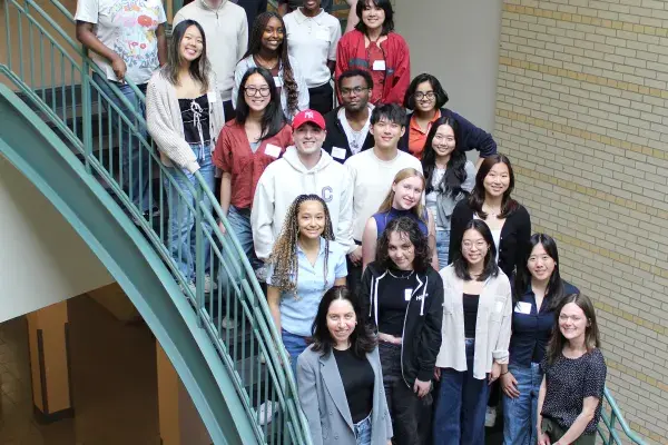 summer 2025 students stand on the green stairs in the atrium 