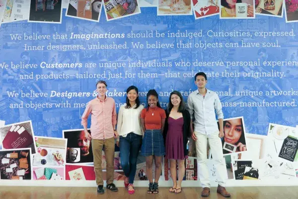 5 team members stand in front of colorful wall with inspirational creativity quote