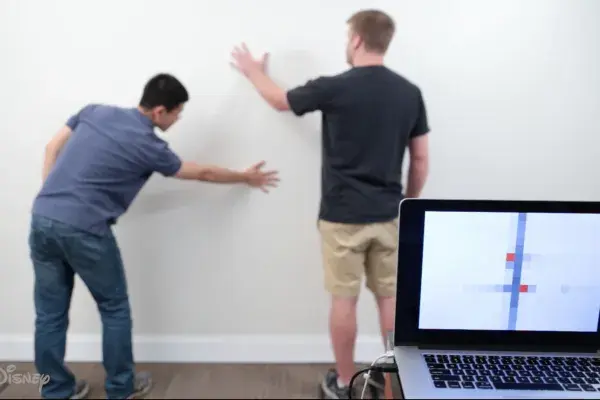 a person touches a wall in 2 places which is recognized by the wall's sensors and displayed on a nearby laptop screen