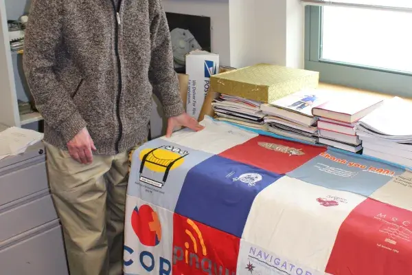 Dan Siewiorek stands beside the t-shirt quilt in his office