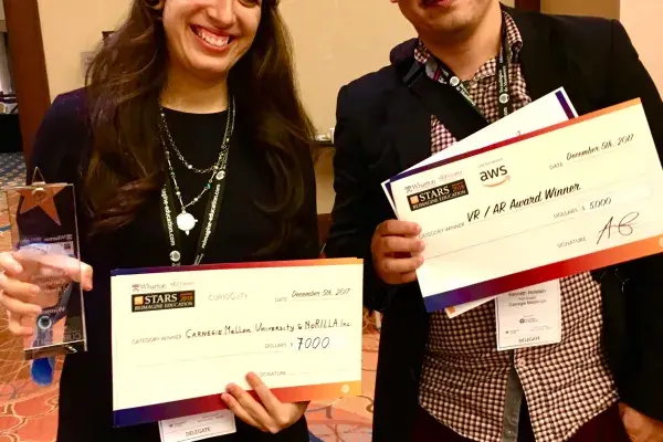 Nesra Yannier and Ken Holstein holding their award checks at the Reimagine Education competition