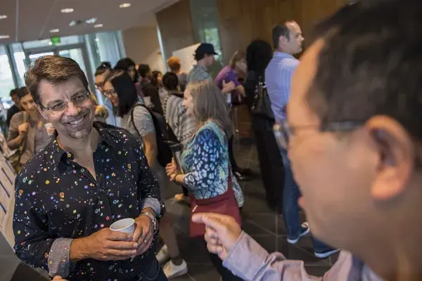 Ken Koedinger converses with others in the hallway during the LearnLab summer school poster session